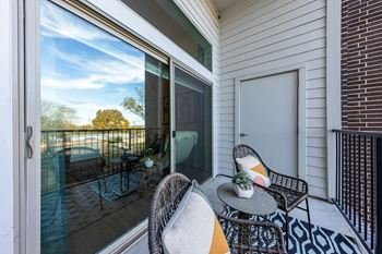 a patio with two chairs and a table on a balcony at The Monroe Apartments, Austin, Texas